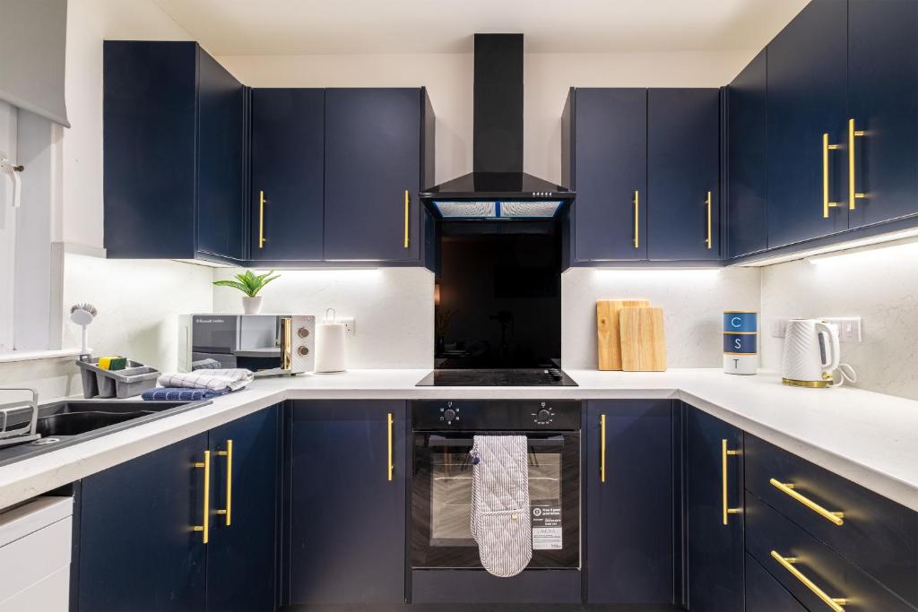 Spital Stay - SJA Stays - Luxury 3 Bed Apartment في أبردين: مطبخ مع دواليب زرقاء وفرن علوي موقد