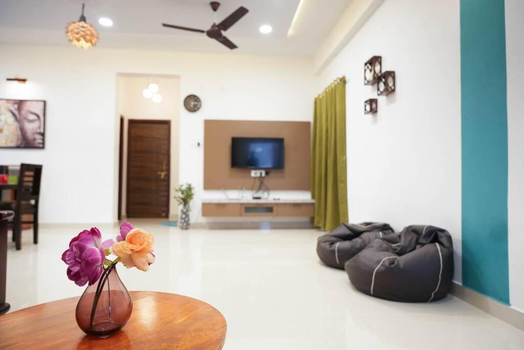 a living room with a vase with flowers on a table at Classe Moyenne -2BHK, Near US Embassy, Gachibowli in Hyderabad