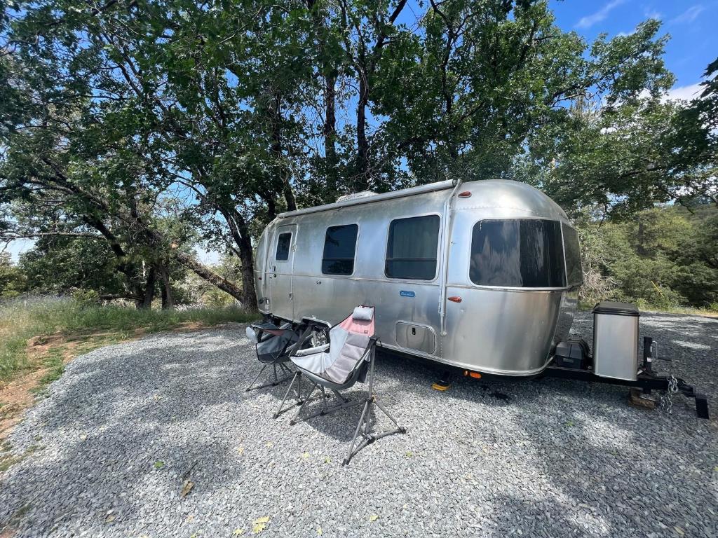 a silver trailer parked in a gravel parking lot at Modern Airstream with amazing view - 10 to 15 minutes from Kings Canyon National Park in Dunlap