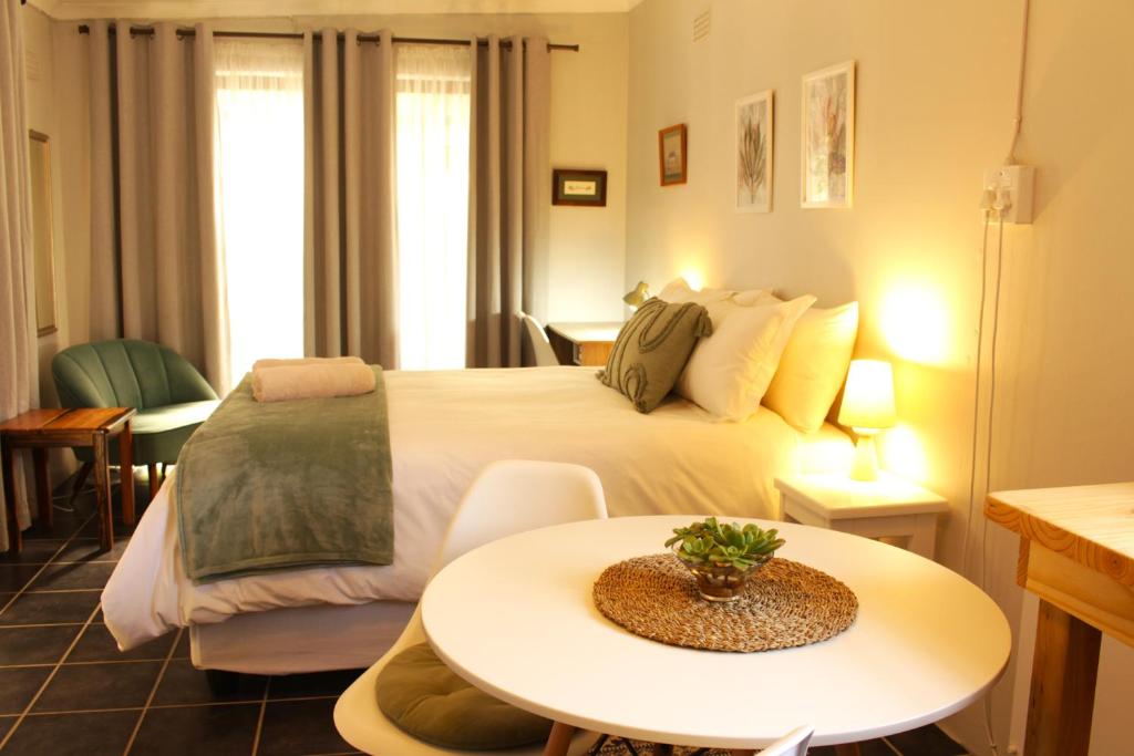 een hotelkamer met een groot bed en een tafel bij Woodlea self-catering flatlet in Pringle Bay