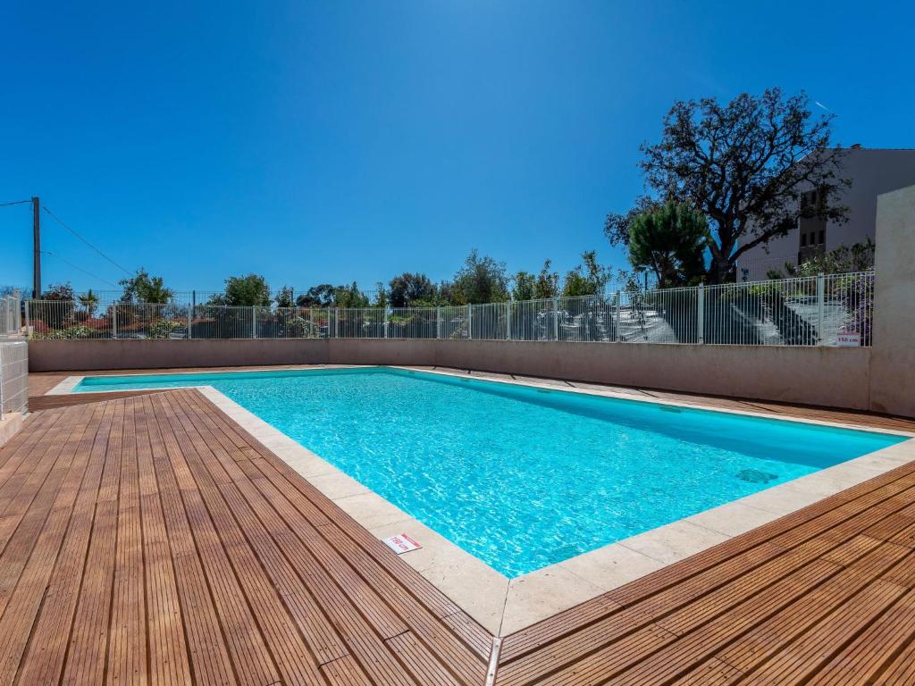 a swimming pool with a wooden deck next to a building at Apartment Le Jardin du Loderi-1 by Interhome in Bormes-les-Mimosas