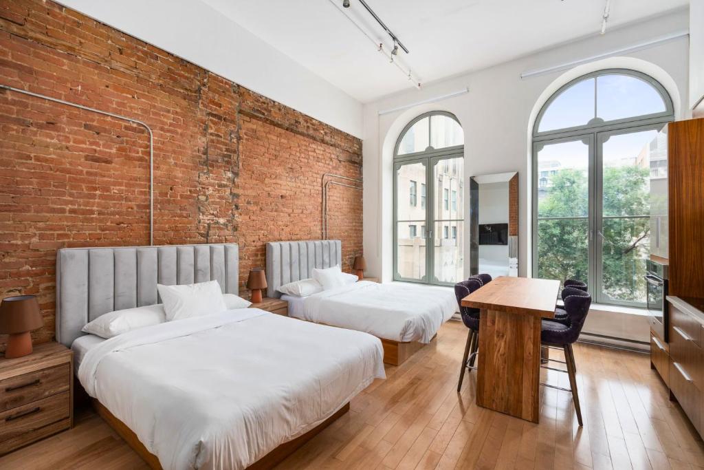 two beds in a room with a brick wall at Le Merrill Boutique Hotel in Montreal