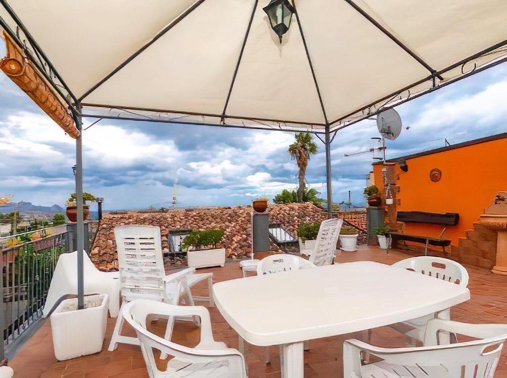 a white table and chairs under an umbrella on a patio at Casa Vacanza La Fontanella in Piedimonte Etneo