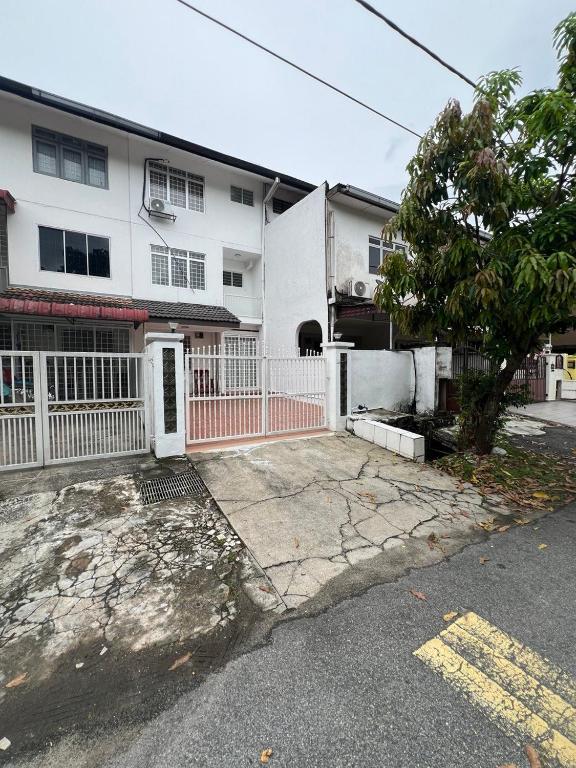 a white house with a white fence and a tree at Dagang Homestay in Ampang