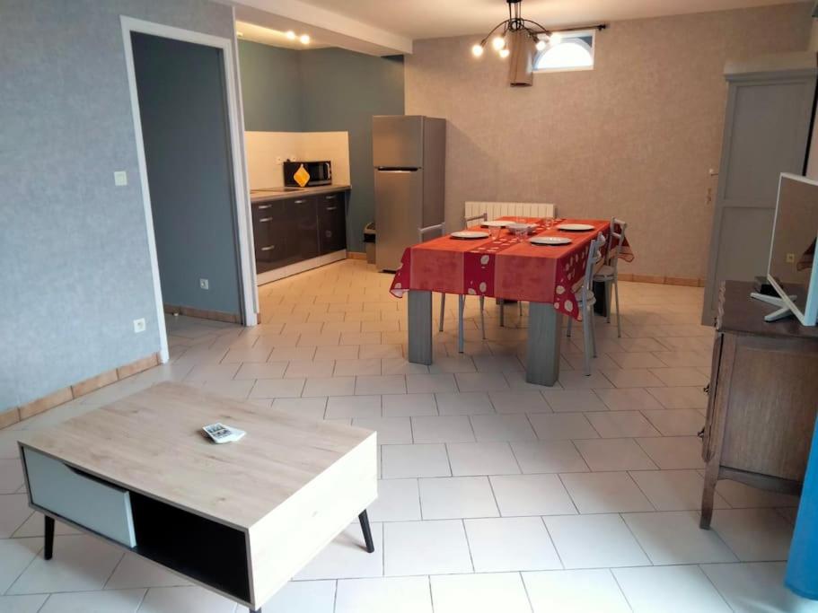 ein Wohnzimmer mit einem Tisch und einer Küche in der Unterkunft Ferme de l'Etang - Gîte in Épuisay