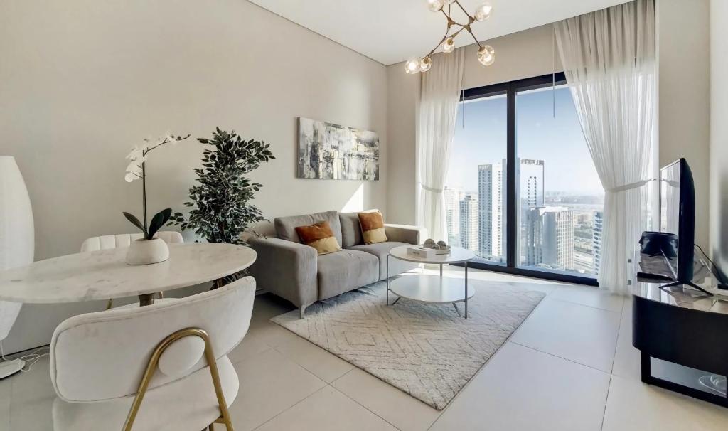 Address Beach Resort Apartment في دبي: غرفة معيشة بيضاء مع أريكة وطاولة