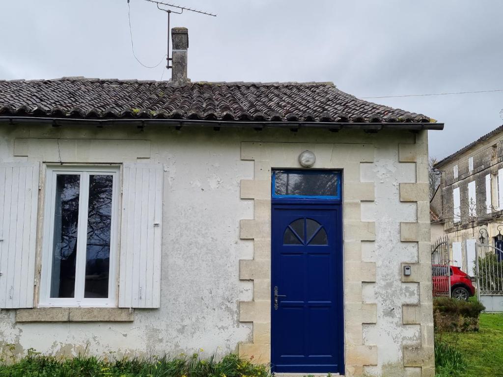 uma pequena casa com uma porta azul e uma janela em Gîte Les Plantis - Cognac em Cherves-de-Cognac