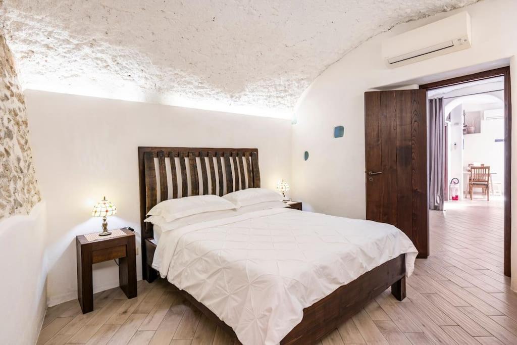 una camera da letto con un letto grande con lenzuola bianche di La casa del '600 Holiday House Amalfi Coast ad Amalfi