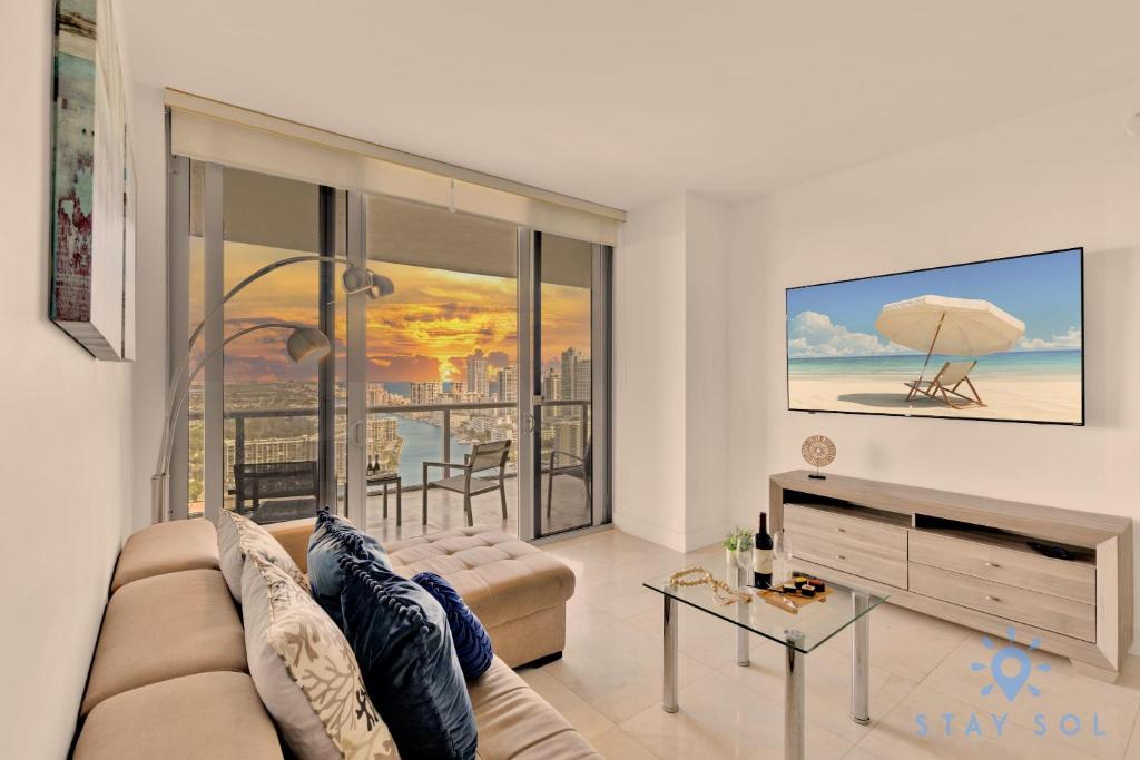 een woonkamer met een bank en uitzicht op de oceaan bij Breathtaking 31st Fl Beachwalk Penthouse View in Hallandale Beach