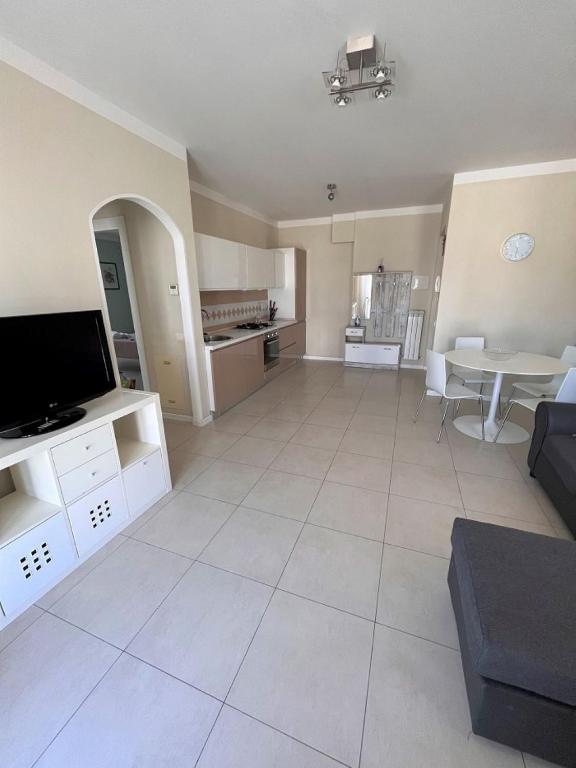 ein großes Wohnzimmer mit einem TV und einem Tisch in der Unterkunft TRILO COPPO CON SPIAGGIA E POSTO AUTO in Numana