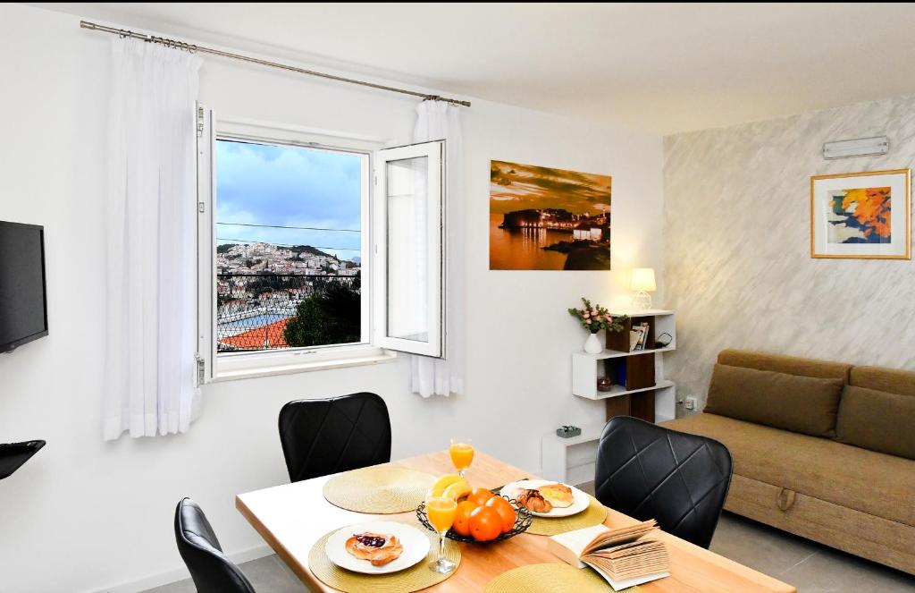 sala de estar con mesa, sofá y ventana en Apartments Pasko, en Dubrovnik