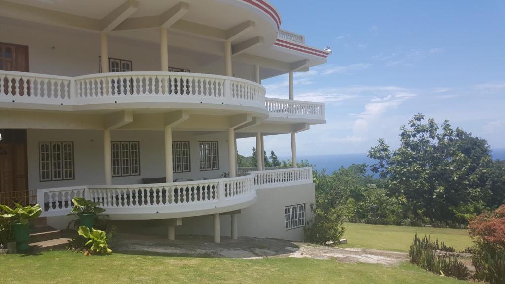a large white house with a balcony on a hill at Barhanna Vista Lodge in Port Antonio