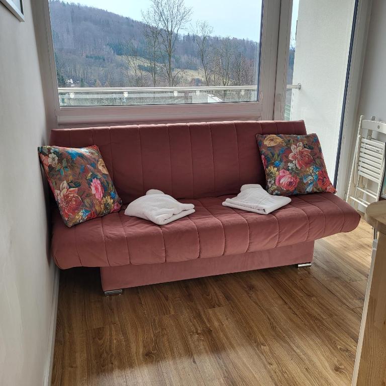 a red couch with pillows in a room with a window at Apartamenty Ustroń Wczasowa 90 in Ustroń