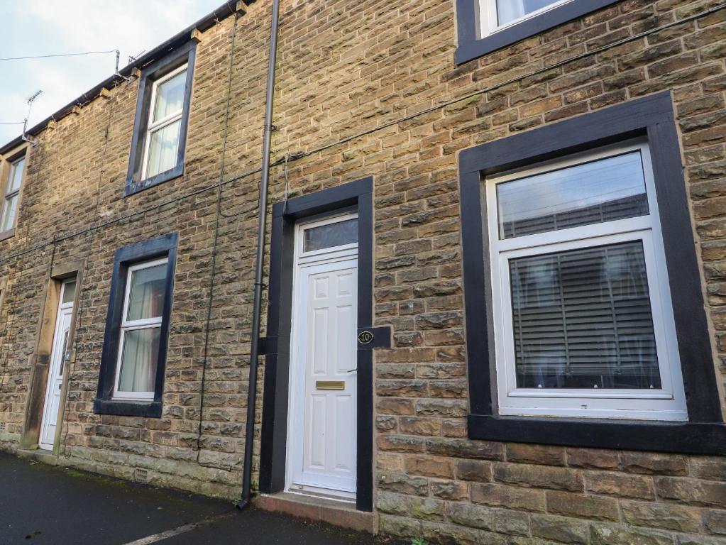 a brick building with a white door and windows at 10 Haw Grove in Skipton
