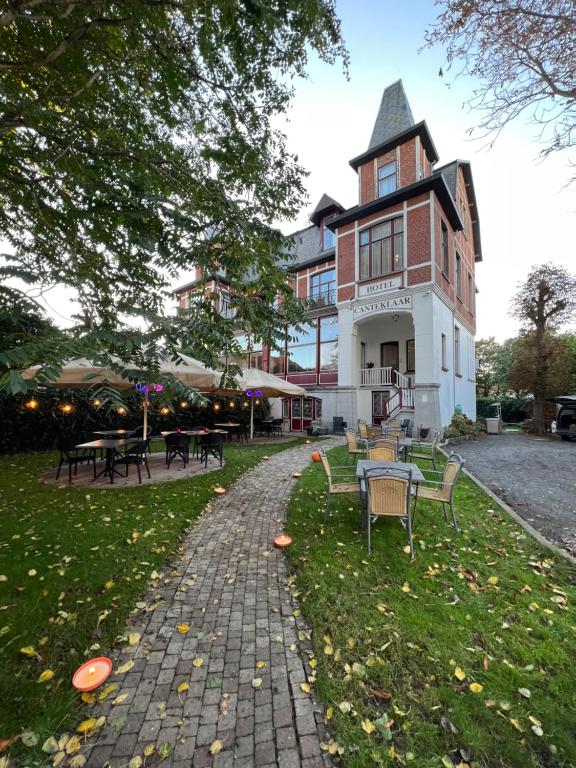 un edificio con mesas y sillas delante de él en Hotel Canteklaar en De Haan