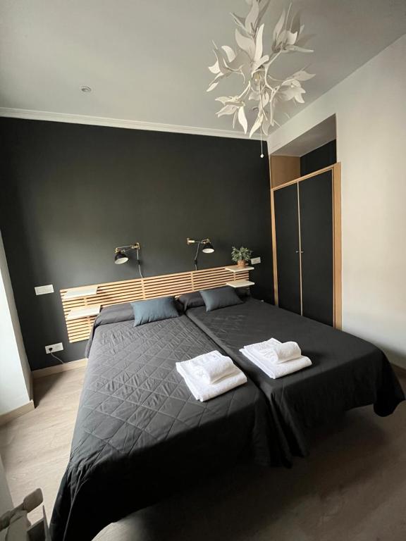una camera da letto con un letto nero con due asciugamani di Hostal Inter Plaza Mayor a Madrid