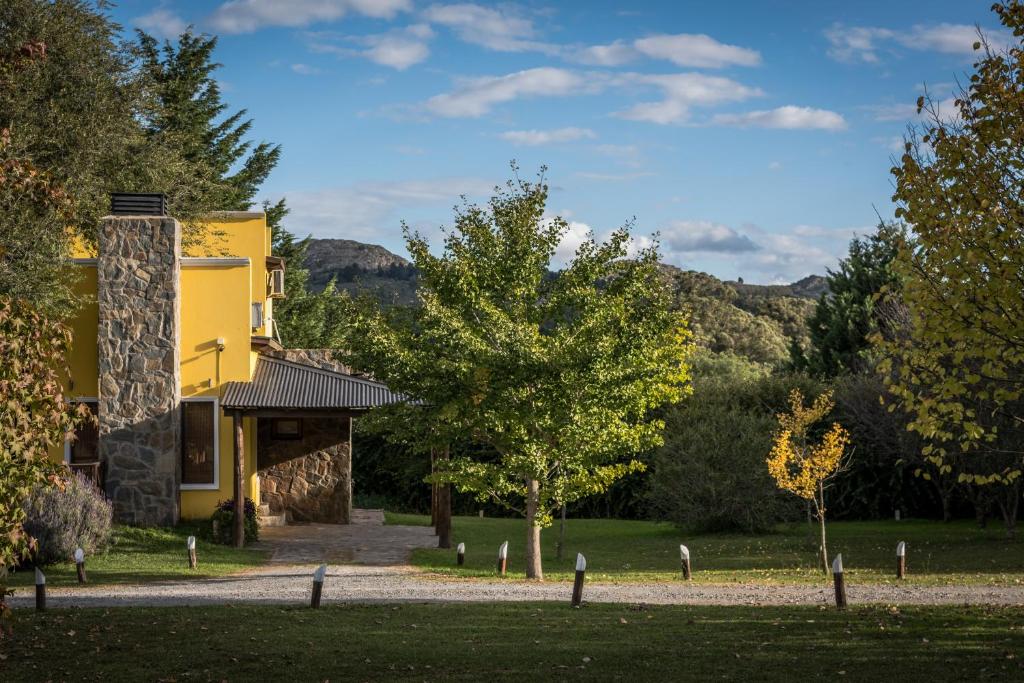 un edificio amarillo con árboles y montañas al fondo en la candelaria en Tandil