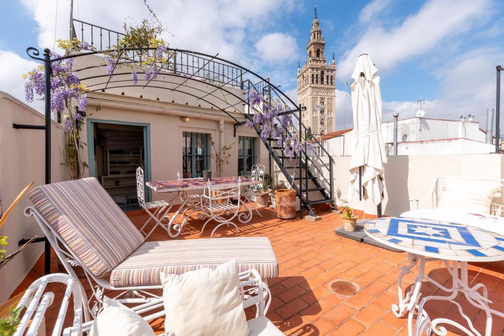 a balcony with chairs and a table and a clock tower at Casa Guadalupe in Seville