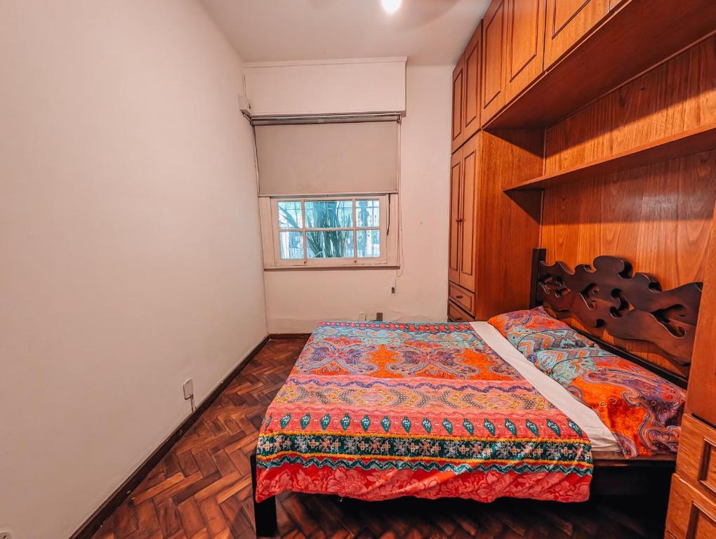 a bedroom with a bed with a wooden headboard and a window at Raridade em Botafogo in Rio de Janeiro