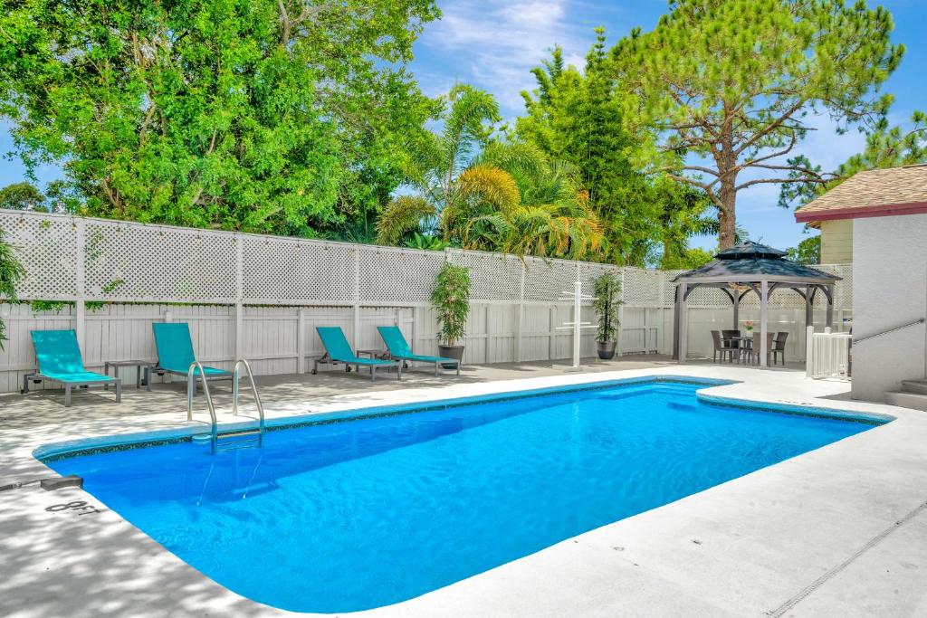 uma piscina com cadeiras azuis e um gazebo em Charming Largo Home with Private Pool 1 Mi to Beach em Largo