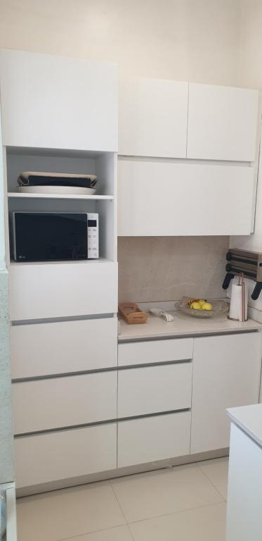 a kitchen with white cabinets and a microwave at Hébergement Marhaba in Dakar