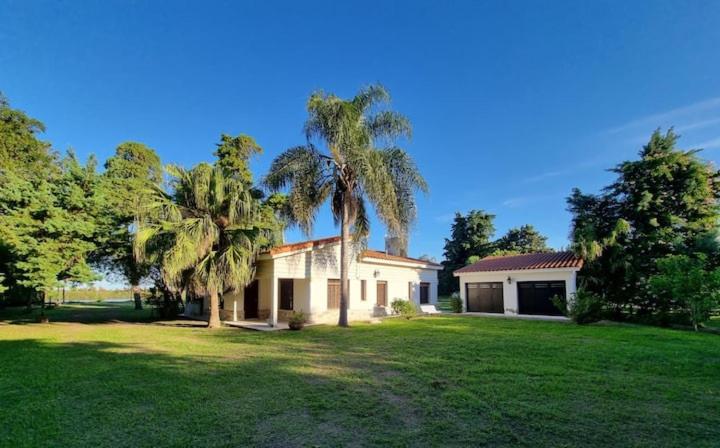 a house with two palm trees in a yard at Espectacular casa quinta al río! in Sauce Viejo