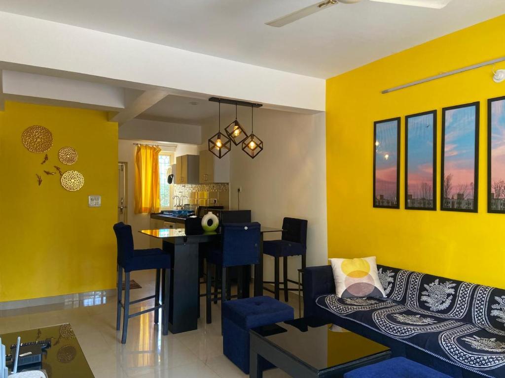 cocina y sala de estar con paredes amarillas y sofá en Serenity Casa, en Talaulim