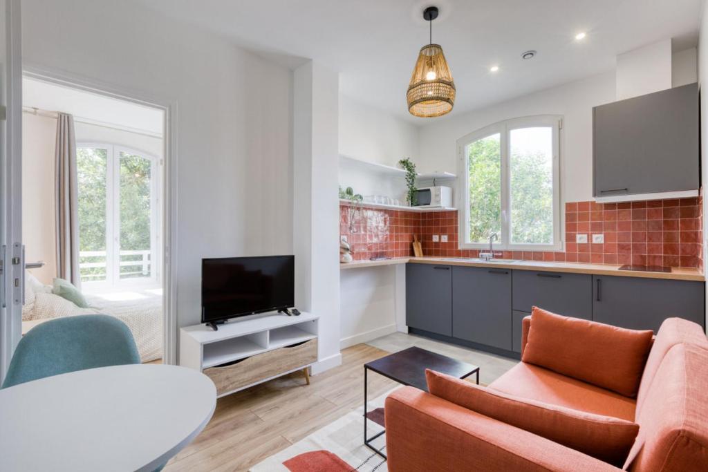 une cuisine et un salon avec un canapé et une télévision dans l'établissement Cocon Terracotta - Appart Cosy - RER Choisy-le-Roi, à Choisy-le-Roi