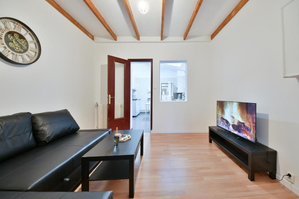 - un salon avec un canapé noir et un réveil dans l'établissement Cozy appartment near Stade de France, à Saint-Denis