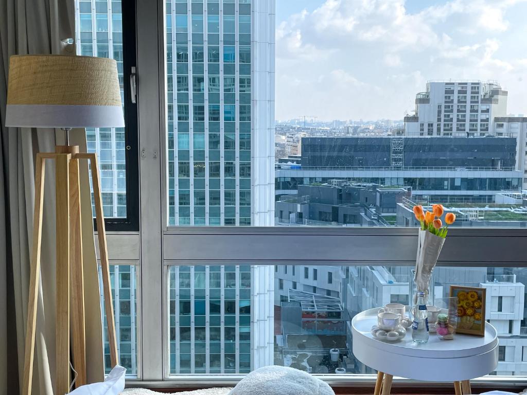 une table avec un vase de fleurs devant une fenêtre dans l'établissement Sur les hauteurs de Montparnasse, à Paris