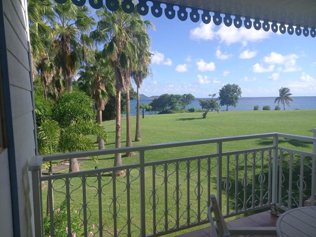 a balcony with a view of the ocean and palm trees at Appartements VUE MER et PARC in Sainte-Luce