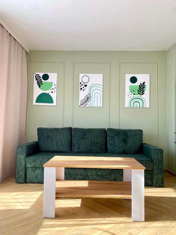 een woonkamer met een groene bank en een tafel bij Apartament Zielone Serce Miasta in Mrągowo