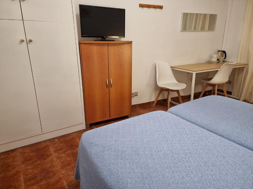1 dormitorio con 1 cama, TV y mesa en Casa de Huéspedes Cuenca, en Madrid