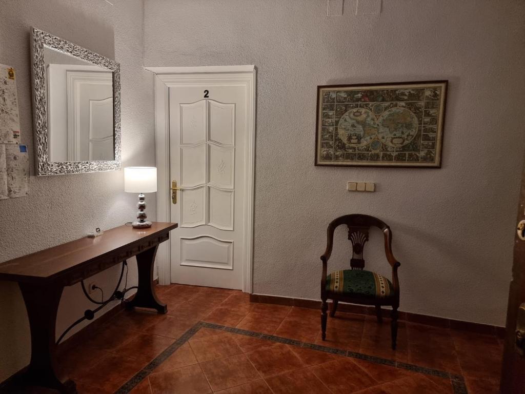 Habitación con escritorio, silla y puerta en Casa de Huéspedes Cuenca en Madrid