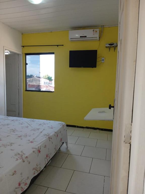 1 dormitorio con 1 cama y TV en la pared en Pousada Bahamas, en Neópolis