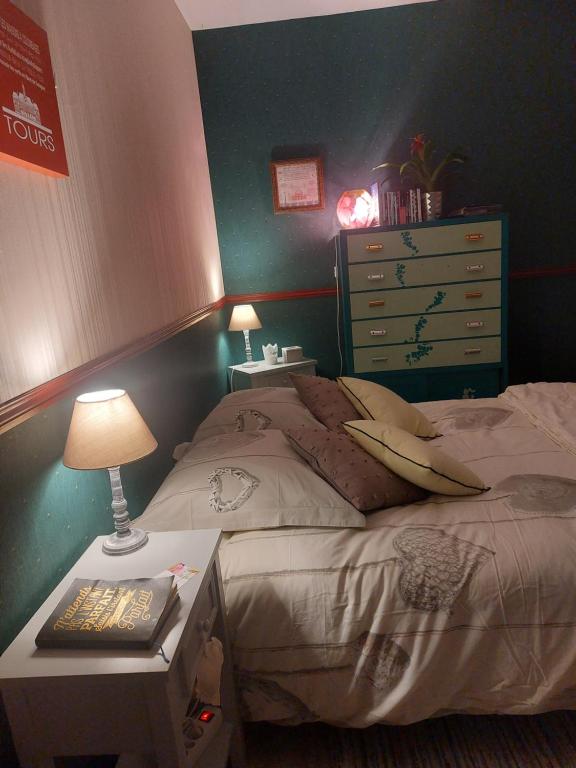 1 dormitorio con 1 cama y 1 mesa con lámpara en Jodelle, en La Riche