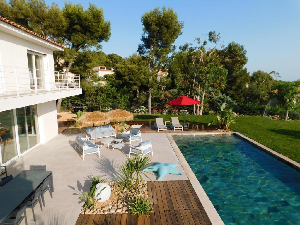 a backyard with a swimming pool and chairs and a house at Villa d'exception piscine privée et vue mer in Saint-Cyr-sur-Mer