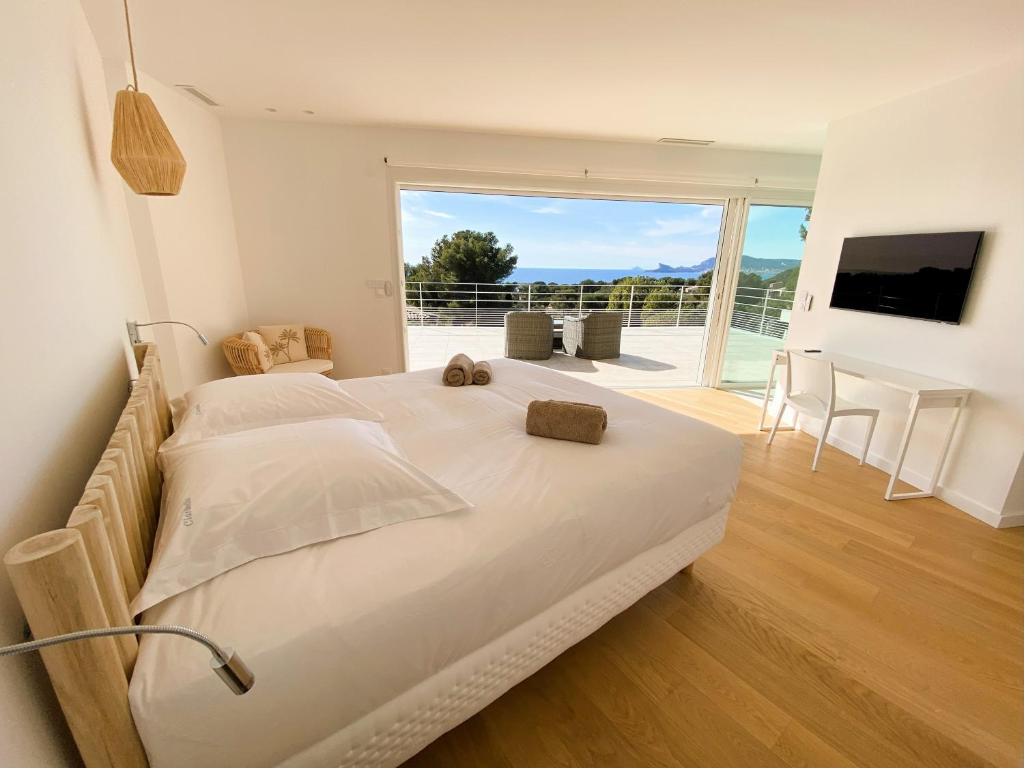a bedroom with a large white bed and a balcony at Villa d'exception piscine privée et vue mer in Saint-Cyr-sur-Mer