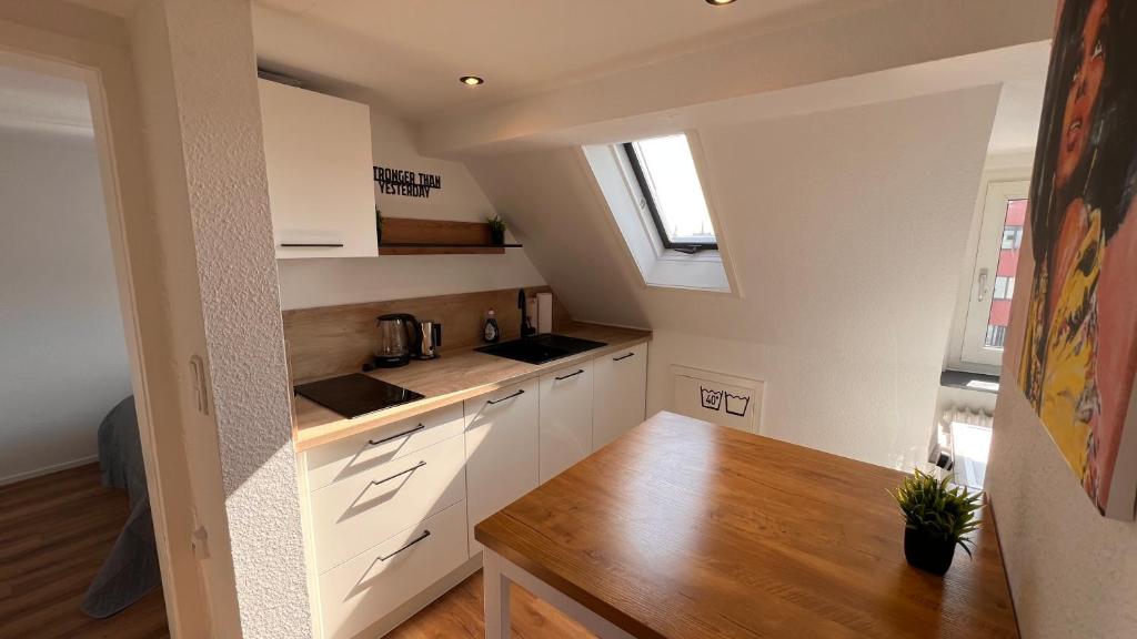a kitchen with white cabinets and a wooden table at 3 Zimmer Apartment mit Parkplatz - Sleepomat in Aschaffenburg