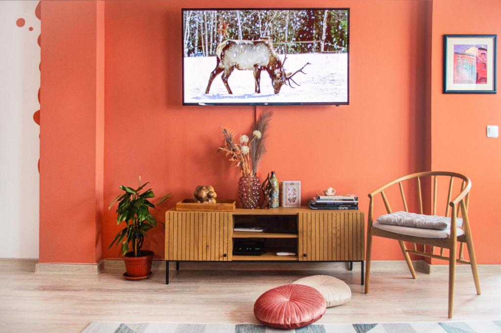 a living room with an orange wall with a tv on it at Апартамент Цвят/ Apartment Colour in Blagoevgrad