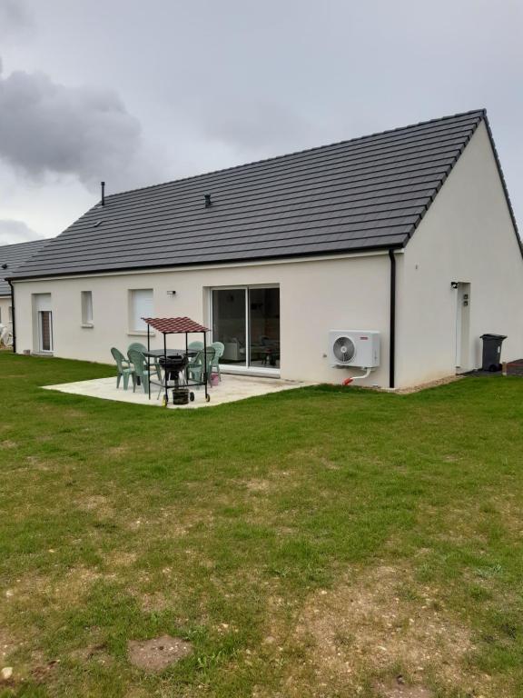 a white building with a picnic table in a yard at Gîte neuf in Dampierre-en-Burly