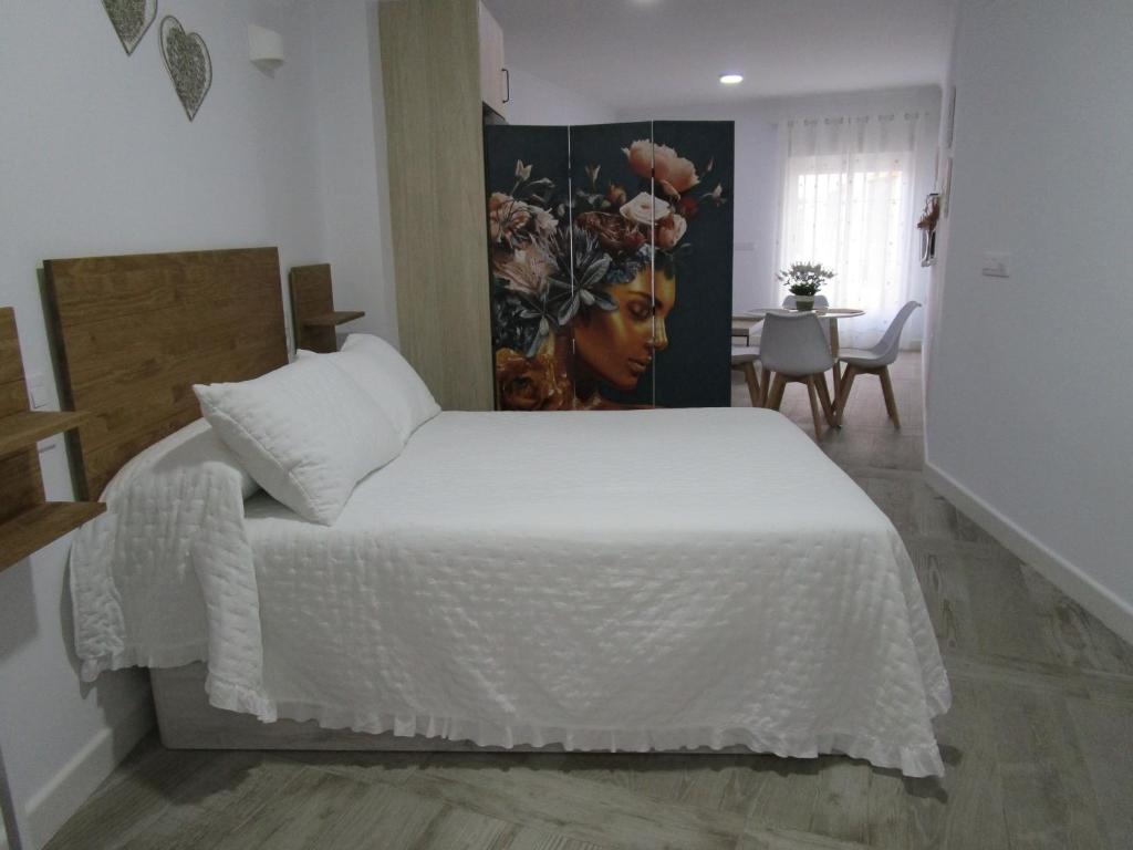 een slaapkamer met een wit bed en een schilderij aan de muur bij APARTAMENTO SOL in Chipiona