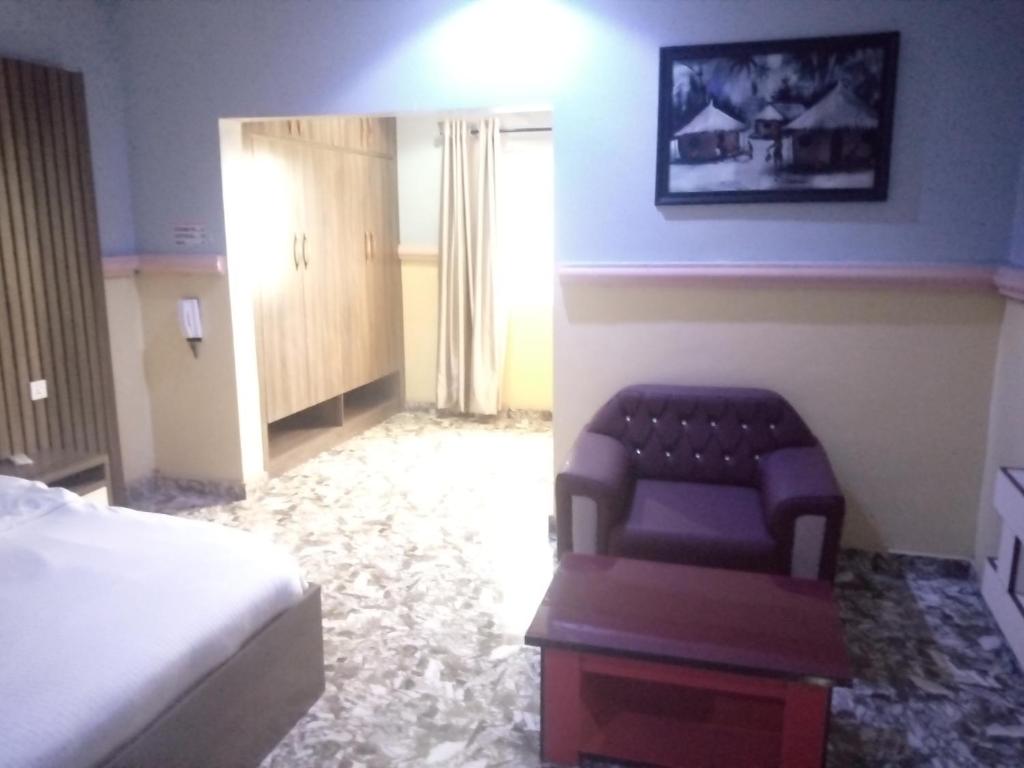 ein Schlafzimmer mit einem Bett, einem Sofa und einem Stuhl in der Unterkunft De Jacob's Hotel & Suites in Umuinya