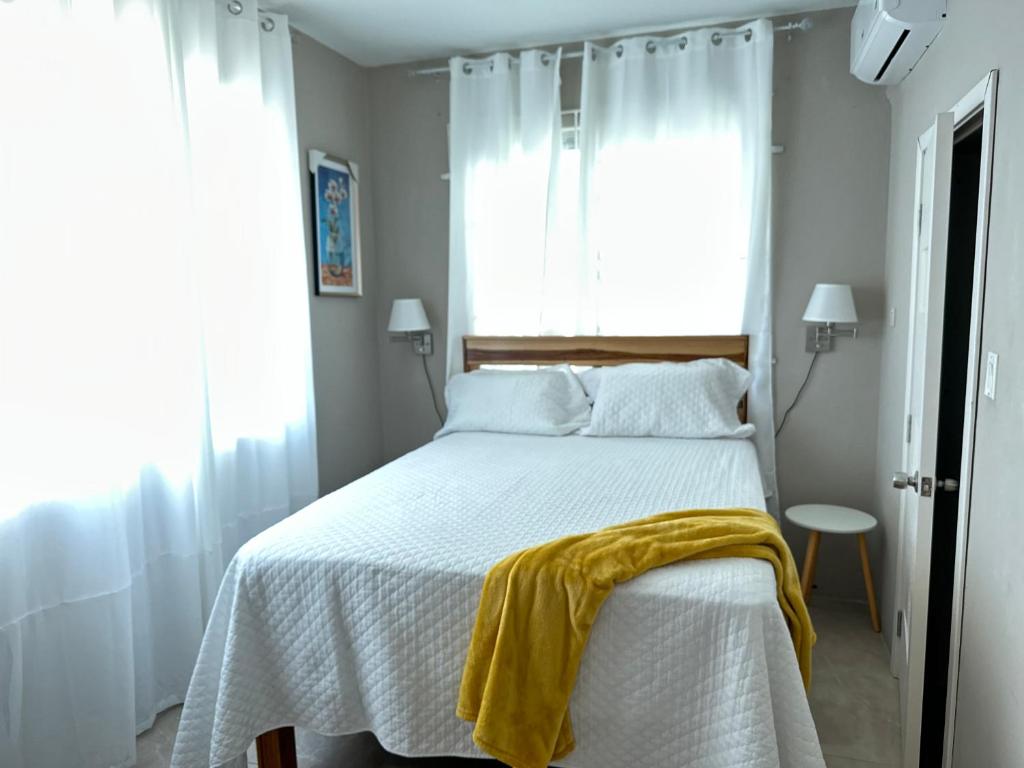 a bedroom with a bed with a yellow blanket on it at The Shelton - Sinclair in Montego Bay