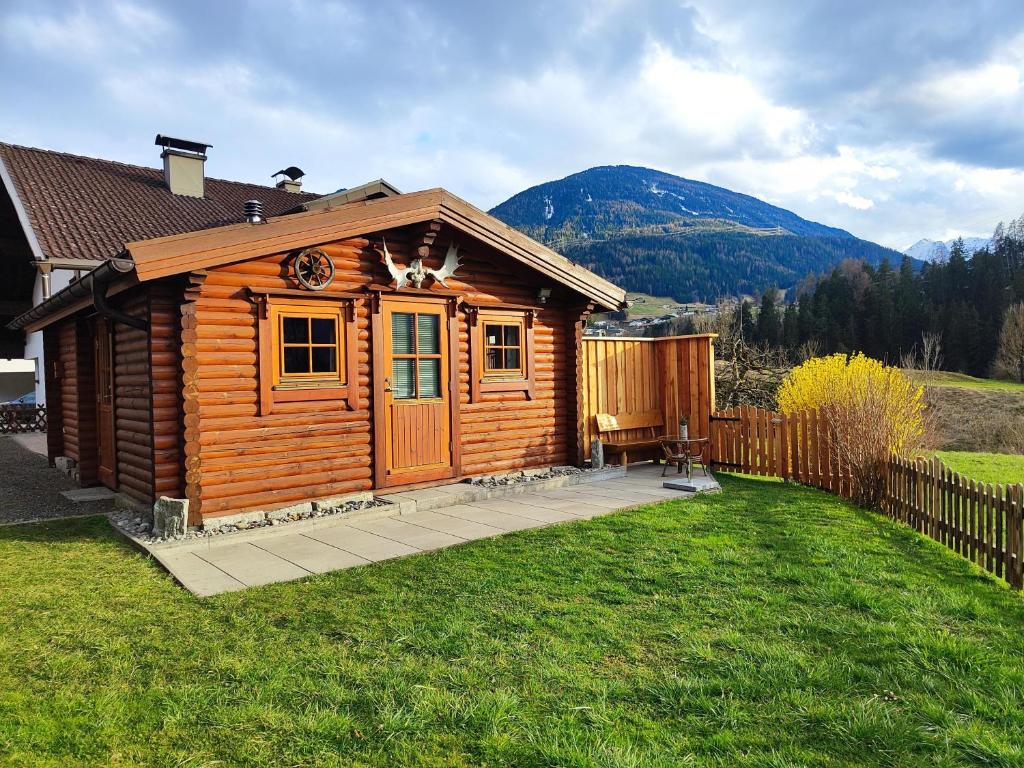 a wooden cabin with a deck in a yard at Harrys Blockhütte in Karres