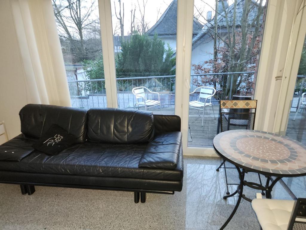 ein schwarzes Ledersofa im Wohnzimmer mit einem Tisch in der Unterkunft Penthouse posh in Troisdorf