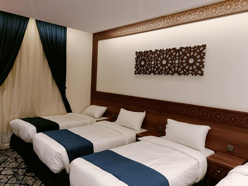a row of three beds in a hotel room at فندق نجمة العزيزية Star AL Aziziyah in Makkah