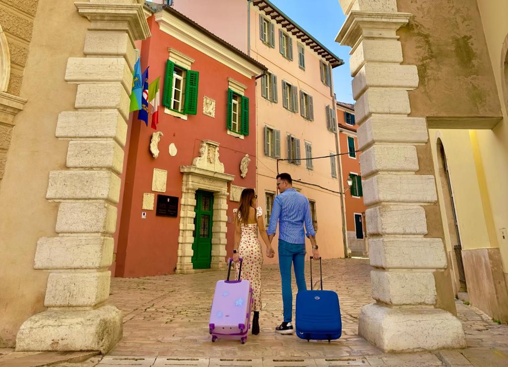 a man and a woman standing with luggage in an alley at CUORE DI ROVIGNO in Rovinj