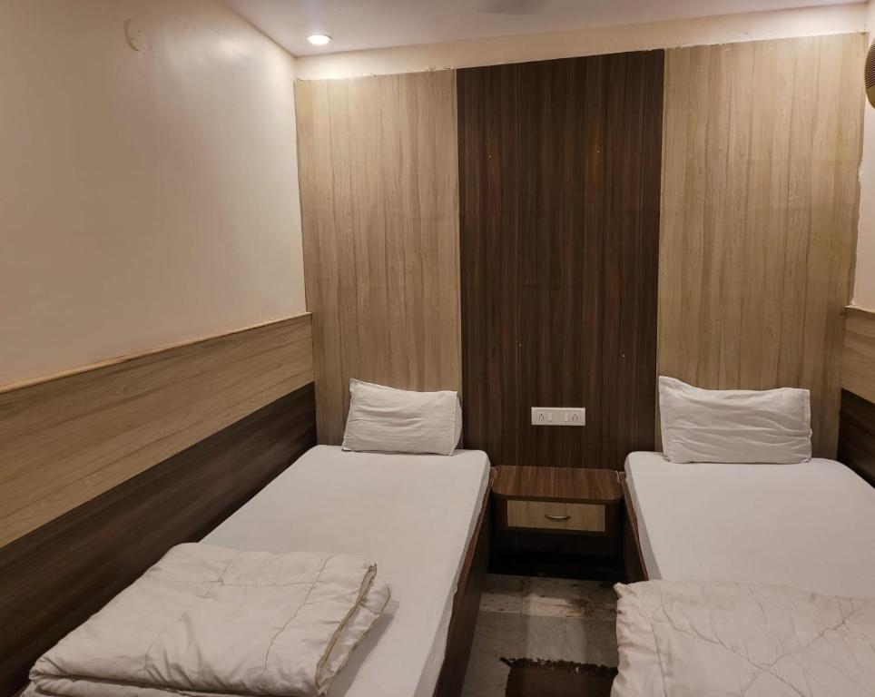 two beds in a small room with wooden walls at HOTEL MERIDIAN in Jamshedpur