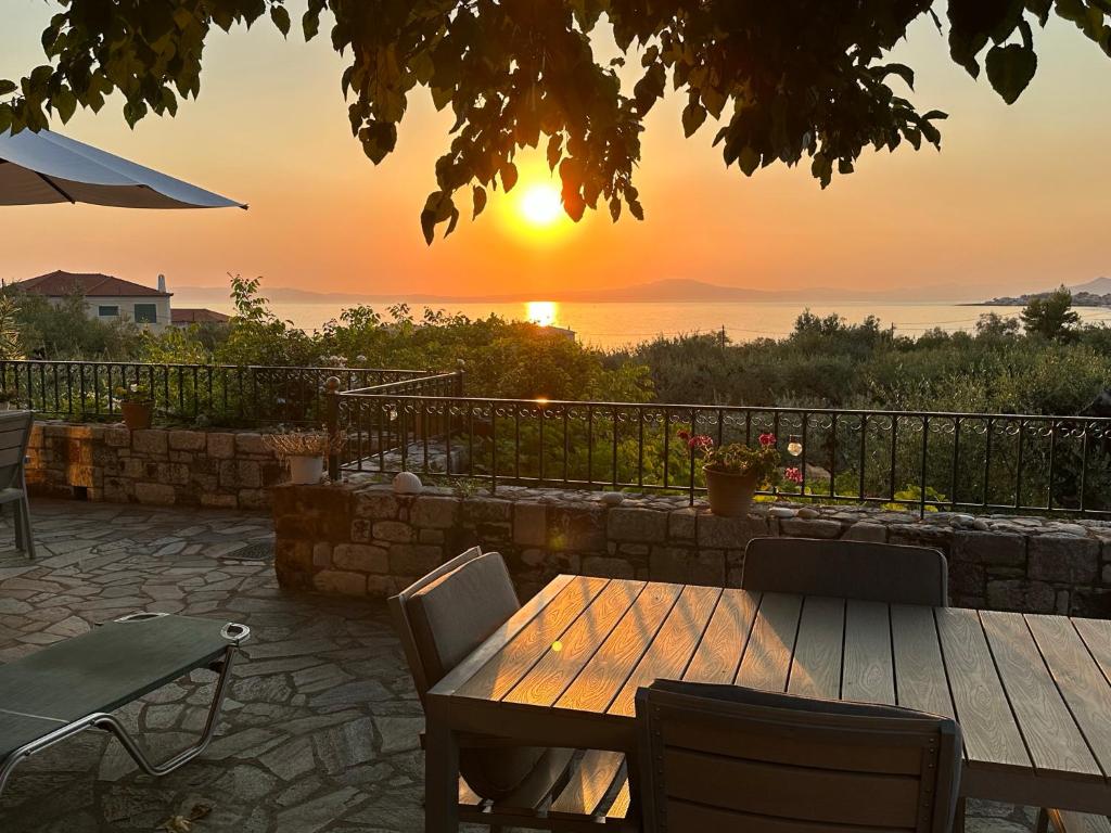 a wooden table and chairs with a sunset in the background at Villa Pefnos in Agios Nikolaos